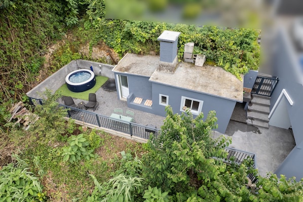 A two-story building with a rooftop garden, a hot tub, and a staircase leading to the upper floor.
