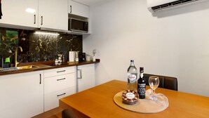 A modern kitchen with white cabinets, a microwave, and an air conditioning unit.