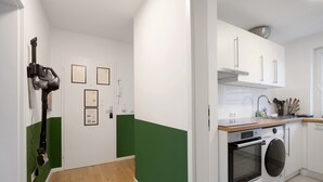 Cozinha com armários brancos, forno embutido, máquina de lavar e bancada de madeira.