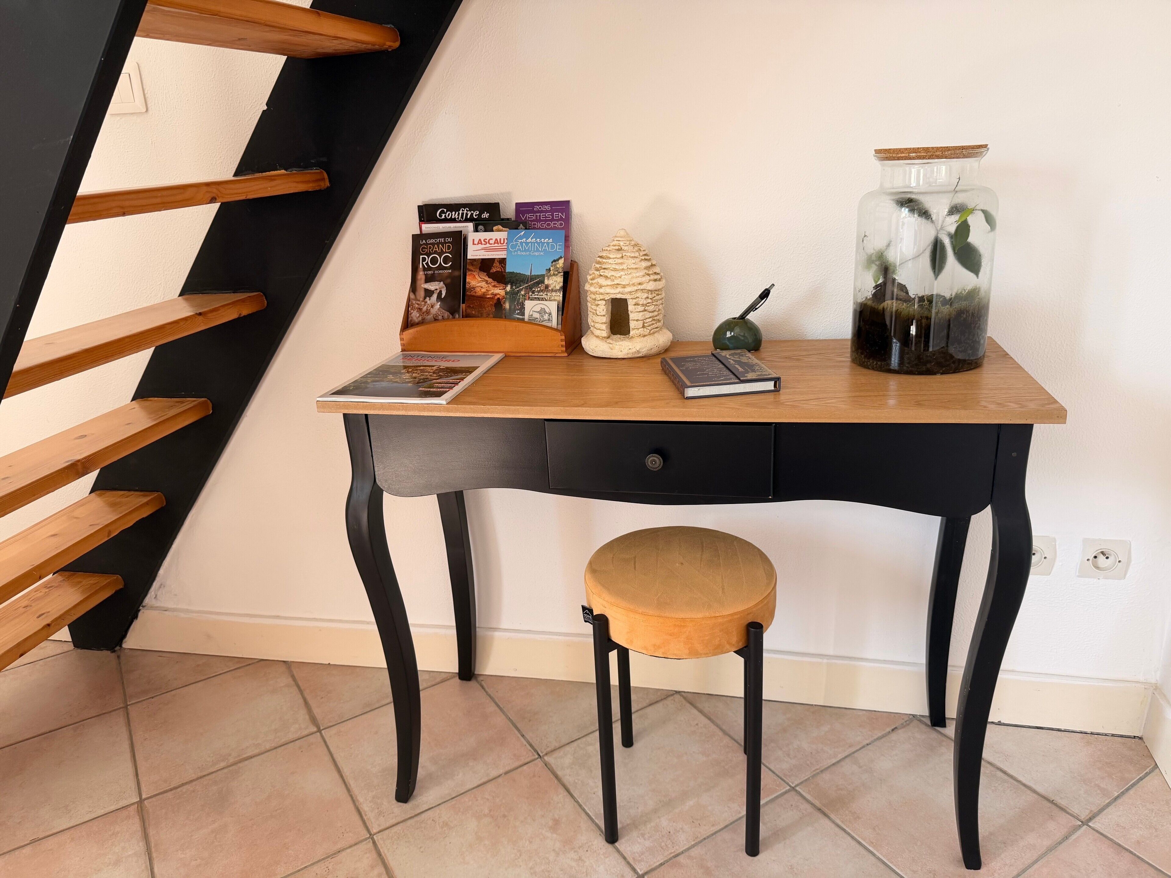A wooden desk with a chair, a small potted plant, and books.