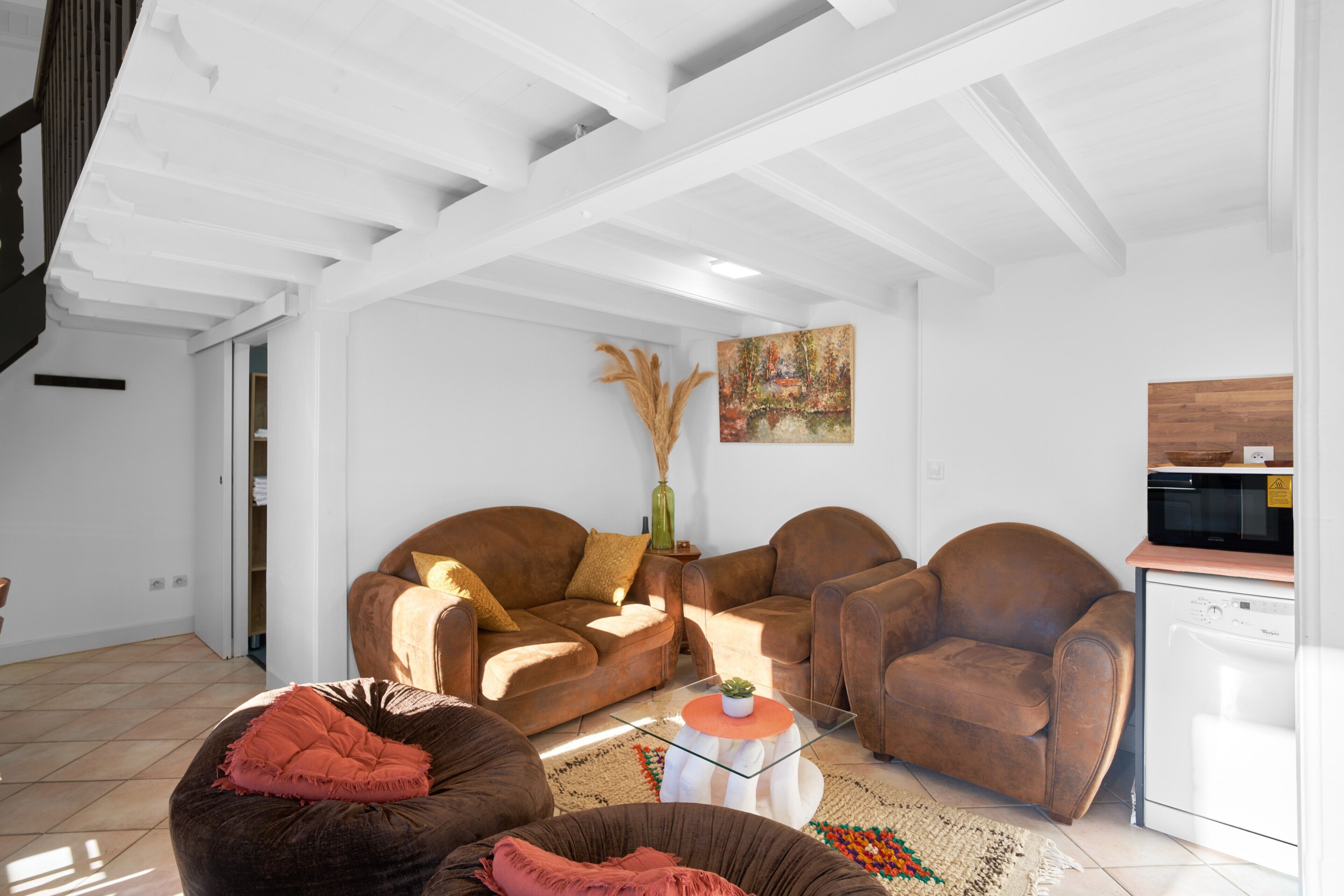 A living room with a sofa set, a coffee table, and a kitchen area with a microwave.