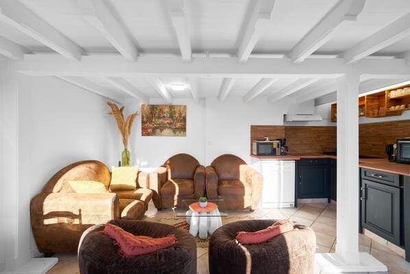 A living room with a sofa set, a coffee table, and a kitchen area with cabinets and appliances.