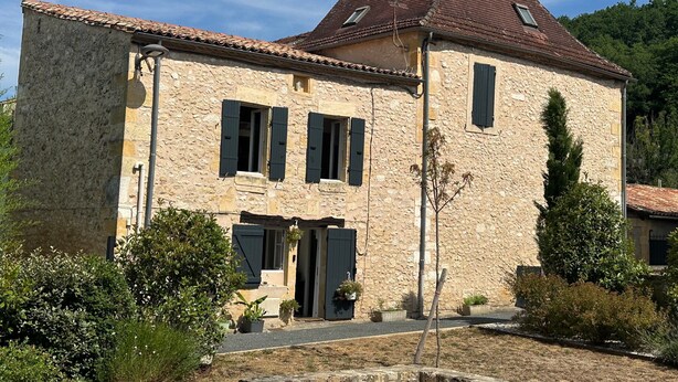 Ein Steinhaus mit Ziegeldach, Schornstein und einem kleinen Fenster mit Fensterläden.