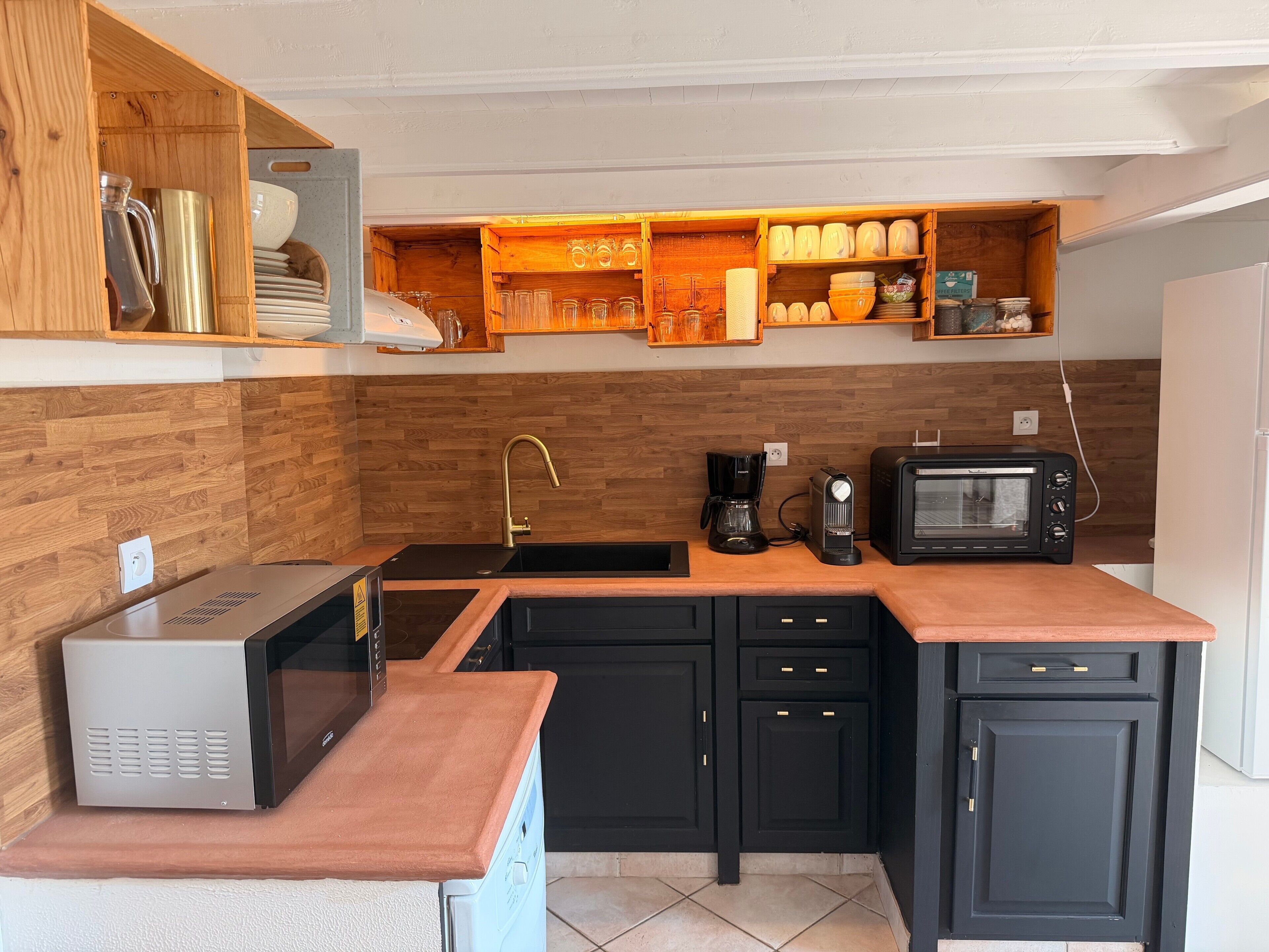 A compact kitchen with a built-in microwave, coffee maker, and toaster oven.