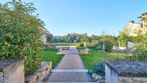 Ein Weg, der durch einen Garten mit Steinrändern und viel Grün führt.