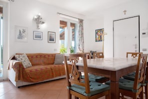 Un comedor con una mesa y sillas, un sofá y una puerta con una cruz.