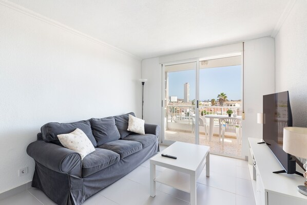 A modern living room with a grey sofa, a white coffee table, and a TV.