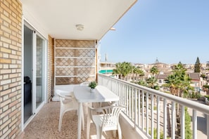 A balcony with a table and chairs, a patterned wall, and a view of a residential area with palm trees.