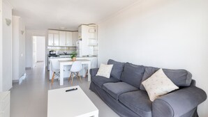 A modern living room with a grey sofa, a white coffee table, and a kitchen in the background. - Apartment 'Bahía Mar' with Sea View, Private Terrace and Wi-Fi (Puerto de Mazarrón)