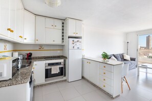 Une cuisine moderne avec des armoires blanches, des comptoirs en granit et un four encastré.