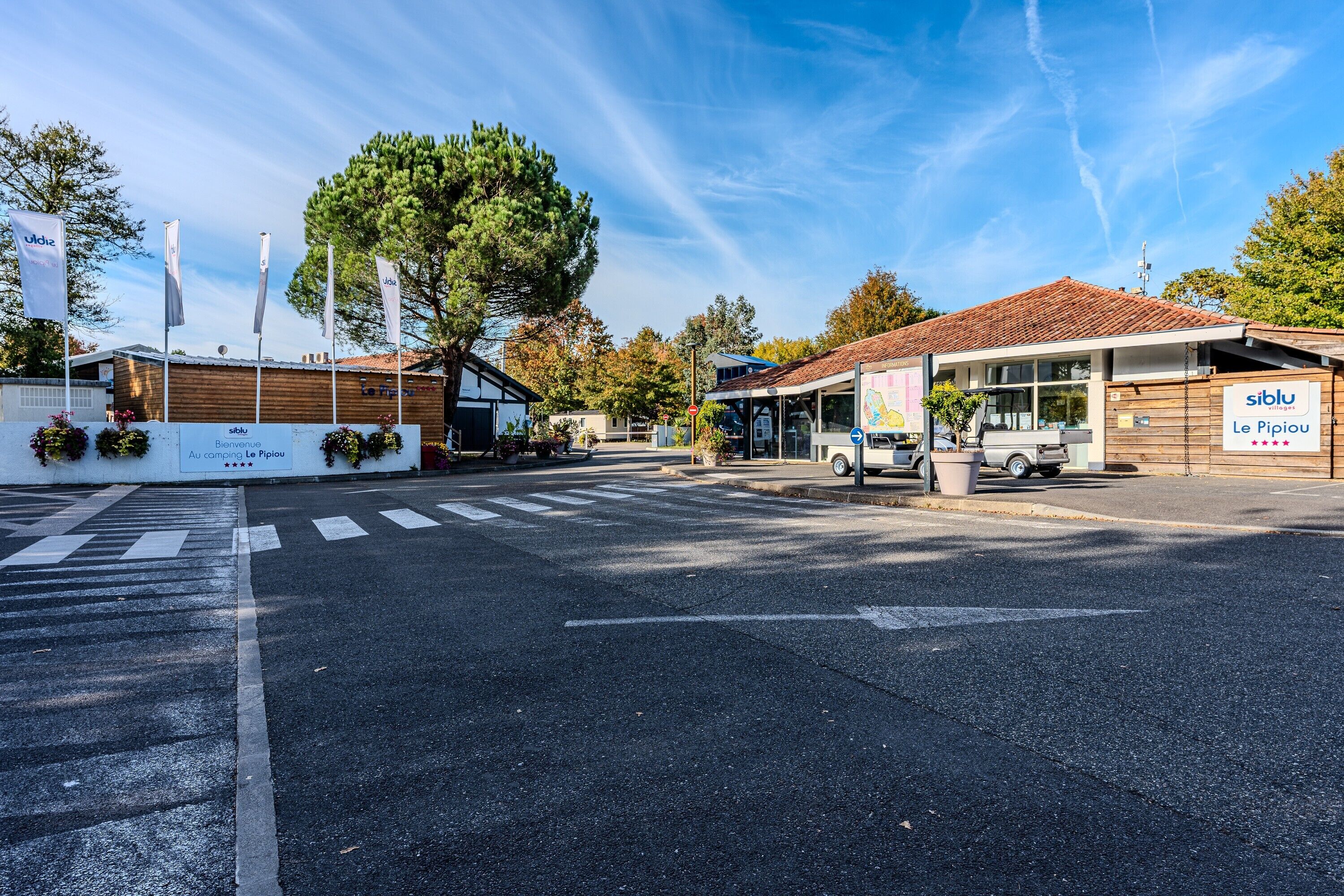 Une vue de rue avec un bâtiment portant l’inscription « siblu Le Pipiou » et un autre bâtiment avec une enseigne « Au camping Le Pipiou ».
