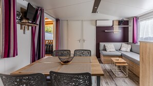 Un espacio habitable compacto con una mesa de comedor, sillas, un sofá y un televisor montado en la pared.