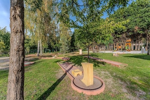 A park with a playground, a large tree, and a circular concrete structure.