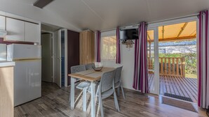 Una cocina compacta con refrigerador, una mesa de comedor con sillas y un puerta corrediza de vidrio que da a una terraza al aire libre.