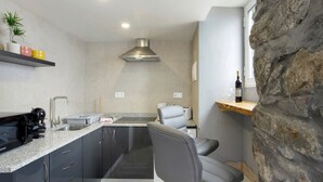 A modern kitchen with granite countertops, a built-in stove, and a stone accent wall.