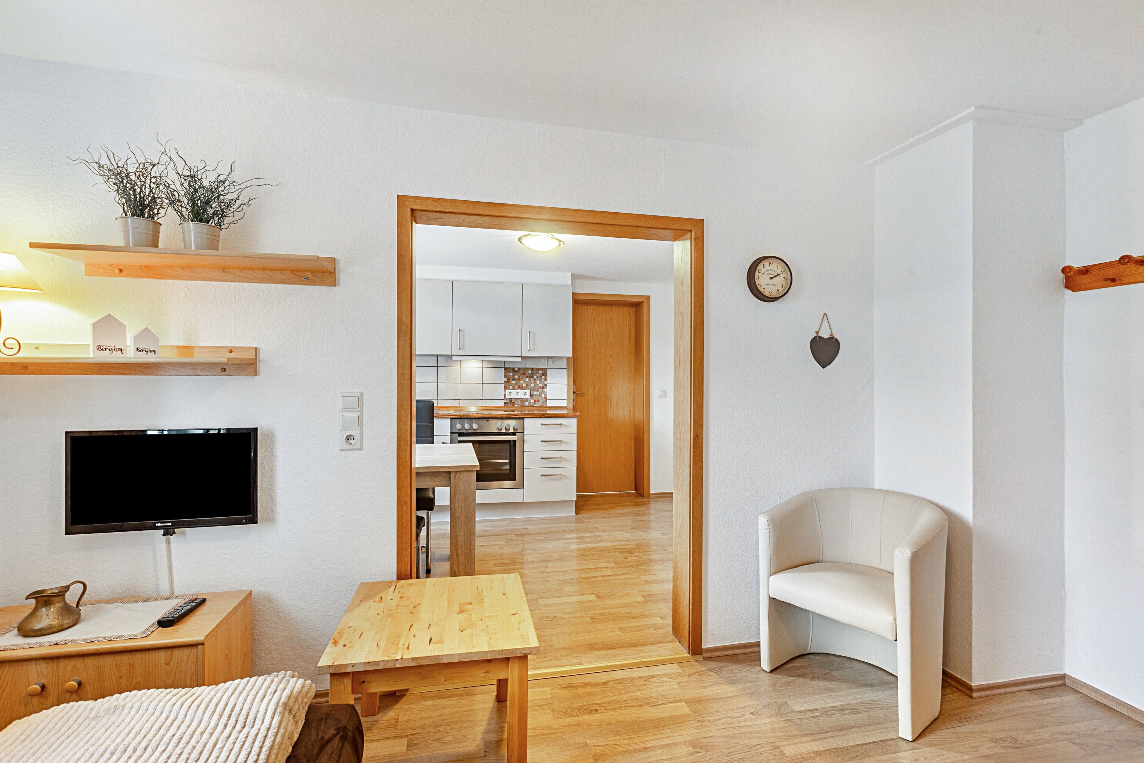 A modern living room with a flat-screen TV, wooden furniture, a small table, and a sofa.