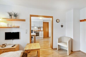 A modern living room with a flat-screen TV, wooden furniture, a small table, and a sofa. - Apartment 'Gänseblümchen' with Shared Terrace and Wi-Fi (Schmallenberg)