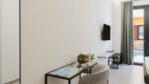 Een moderne kamer met een flatscreen televisie aan de muur, een tafeltje met een wereldbol en een plant, een stoel en een bank.