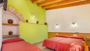 Un dormitorio con dos camas, un arco de piedra, estantes con cerámica e iluminación en la pared.