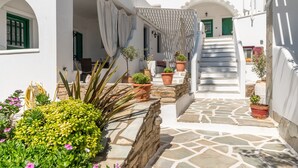 Un bâtiment blanc avec un escalier en pierre, des plantes en pot et une enseigne au-dessus de l’entrée.