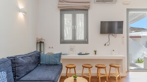 Un salon moderne avec un canapé, un téléviseur, une fenêtre avec des stores et un balcon.