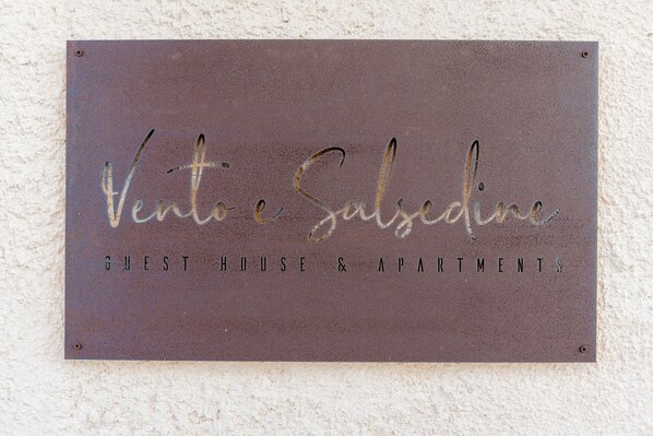 A sign for 'Vento Salsedine Guest House & Apartments' with a rustic, weathered metal finish.