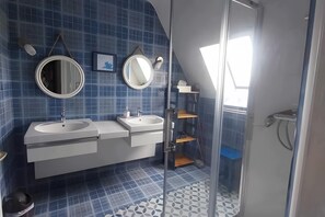 A bathroom with two sinks, a mirror, a shower, and a window.