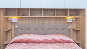A bedroom with a bed, wooden headboard, and two bedside lamps.