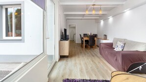 Una sala de estar moderna con un sofá, una mesa de comedor con sillas y una cocina al fondo.