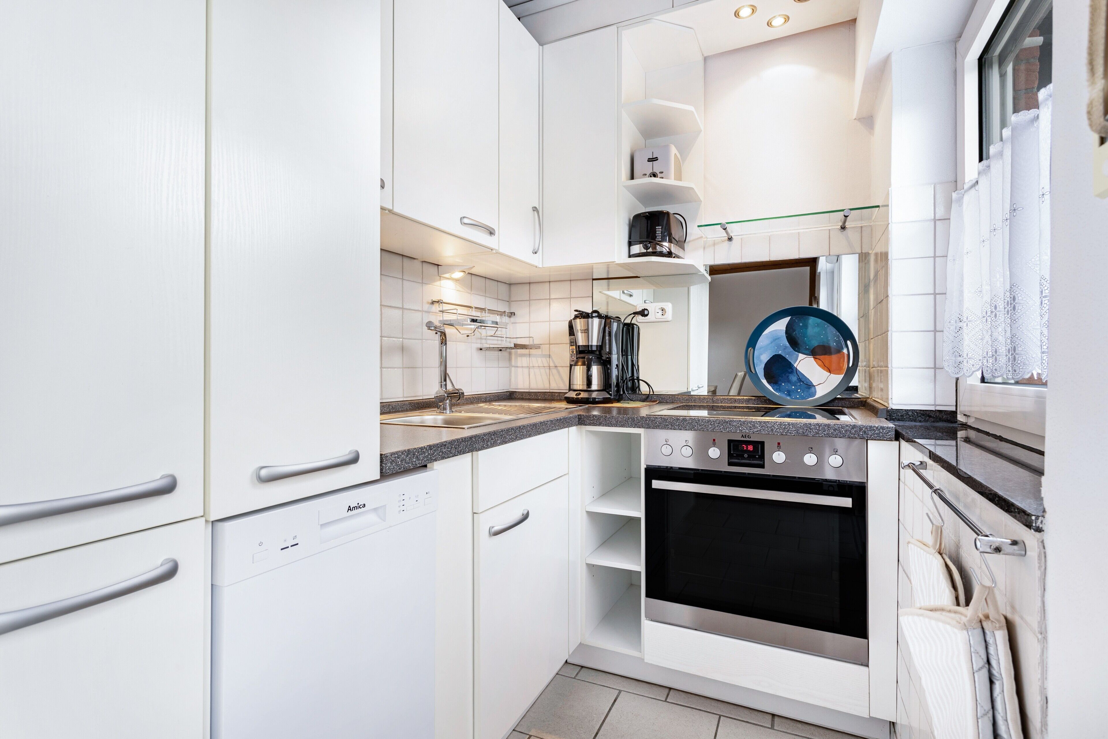 A modern kitchen with white cabinetry, a built-in oven, and a coffee maker.