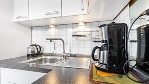 Ett modernt kök med en diskho i rostfritt stål, en kaffebryggare och en vattenkokare.