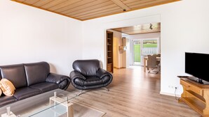 Ett modernt vardagsrum med en soffa i läder, ett soffbord i glas, en TV-möbel i trä och en tv.