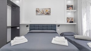 A modern hotel room with a large bed, two smaller beds, a wardrobe, and artwork on the walls. - Room 'Dolce Relax - Classic' with Balcony, Wi-Fi and Air Conditioning (Catania)