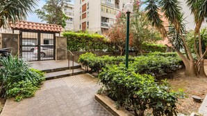 A courtyard with a tiled walkway, a gate, and a building with balconies. - Room 'Dolce Relax - Classic' with Balcony, Wi-Fi and Air Conditioning (Catania)