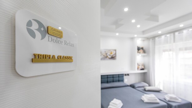 A hotel room with a bed, a wall-mounted sign, and a window with curtains. - Room 'Dolce Relax - Classic' with Balcony, Wi-Fi and Air Conditioning (Catania)