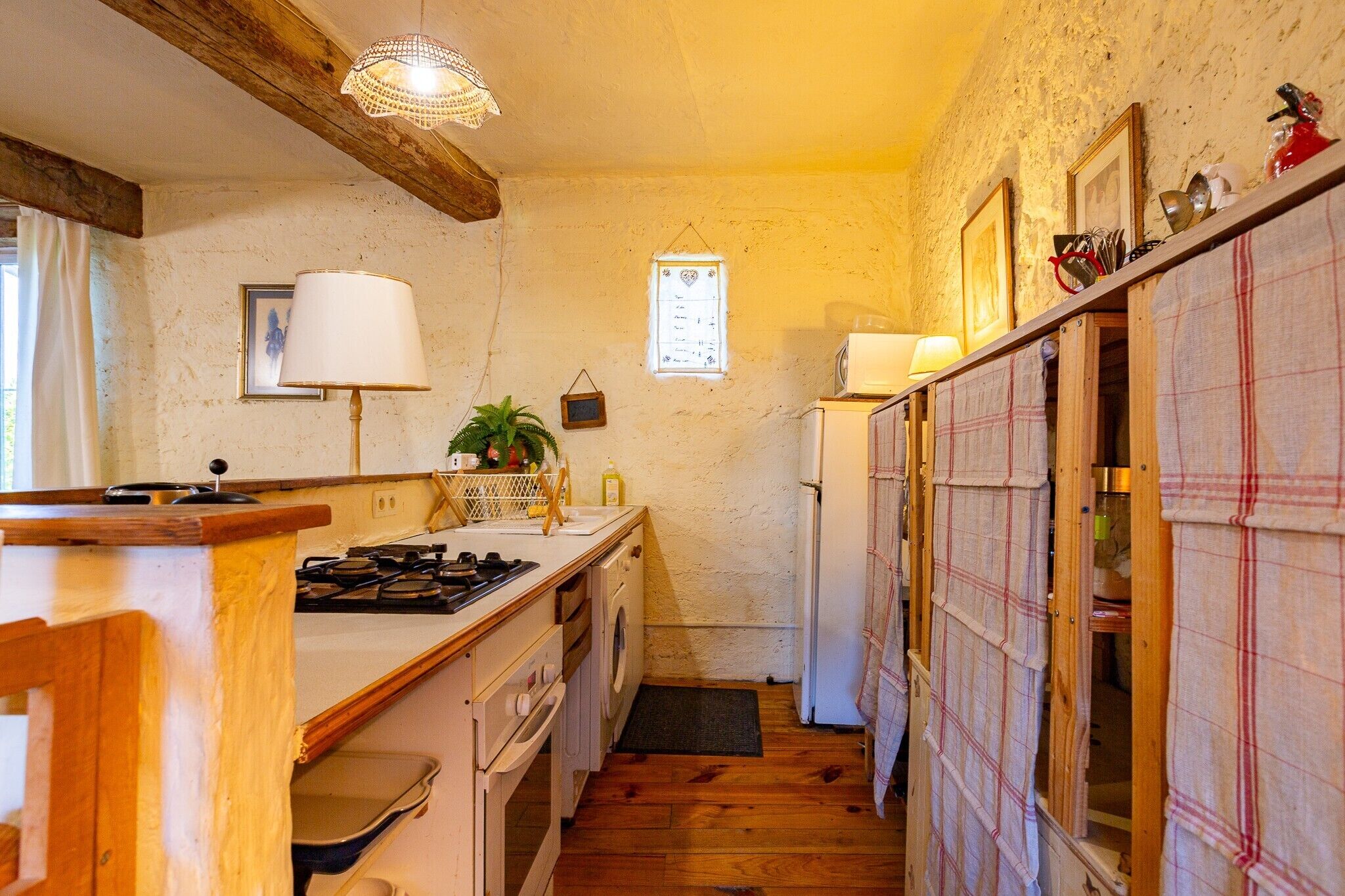 Una cocina con armarios de madera, estufa, pileta y refrigerador.