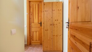 A wooden door with a handle, a light switch on the wall, and a tiled floor. - Room 'Habitació Triple' with Mountain View, Wi-Fi and Air Conditioning (Conques)