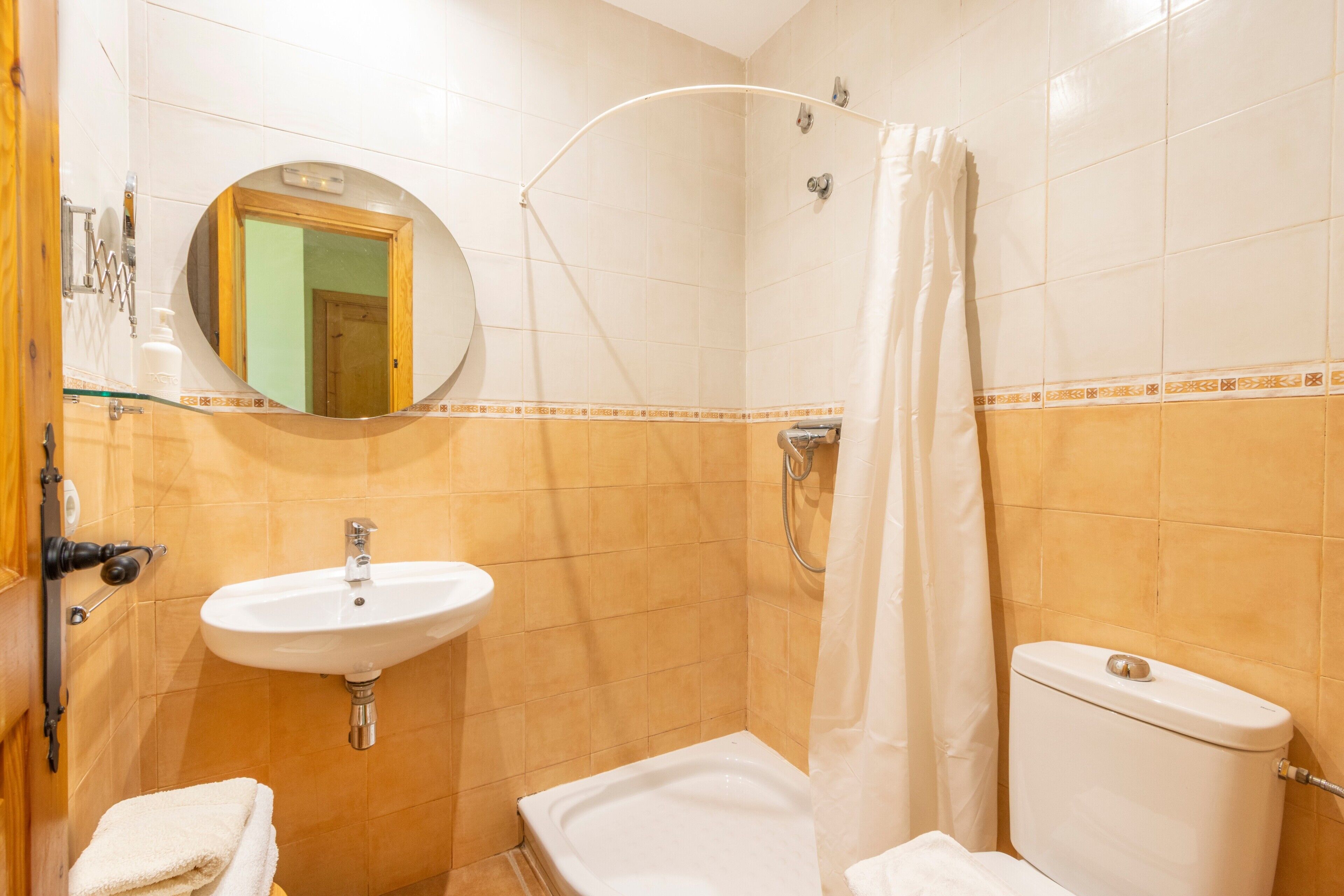 A bathroom with a sink, toilet, shower, and a mirror.