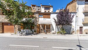 A street view with a building labeled 'Alotament Rural,' featuring a small outdoor seating area with chairs and tables. - Room 'Habitació Triple' with Mountain View, Wi-Fi and Air Conditioning (Conques)