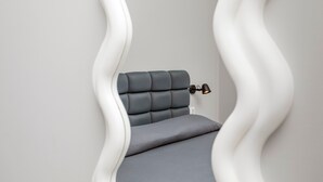 A modern bed with a headboard and a bedside lamp in a minimalist room. - Room 'Dolce Relax - Deluxe' with Balcony, Wi-Fi and Air Conditioning (Catania)