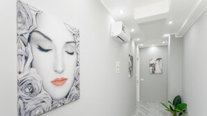 A hallway with a large floral artwork on the wall, a potted plant, and a ceiling-mounted air conditioning unit. - Room 'Dolce Relax - Deluxe' with Balcony, Wi-Fi and Air Conditioning (Catania)