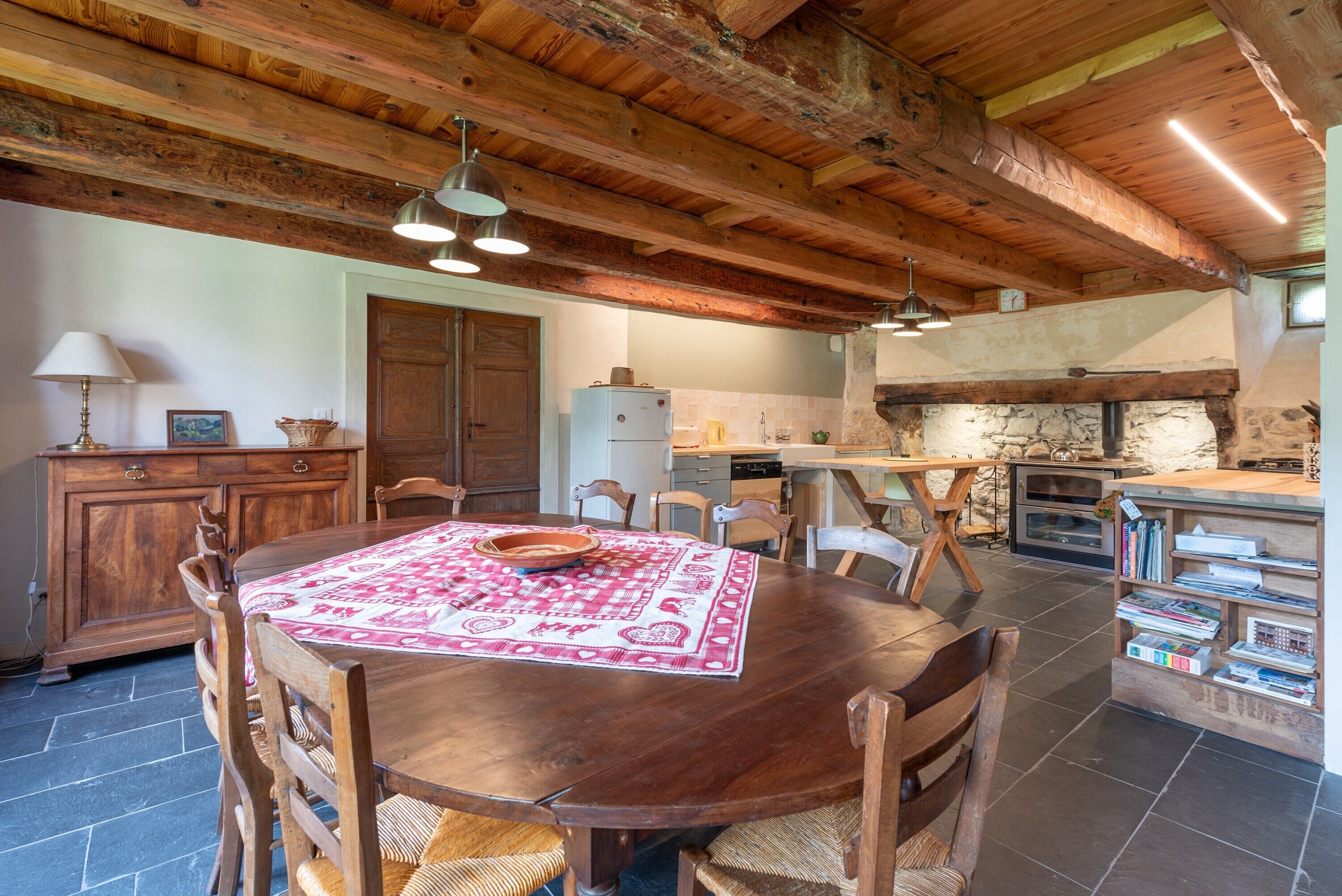 A rustic dining area with a wooden table, chairs, and a patterned tablecloth.