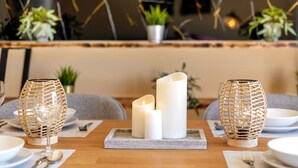 Une table à manger décorée de bougies, d’un chandelier en verre et d’un autre en osier.