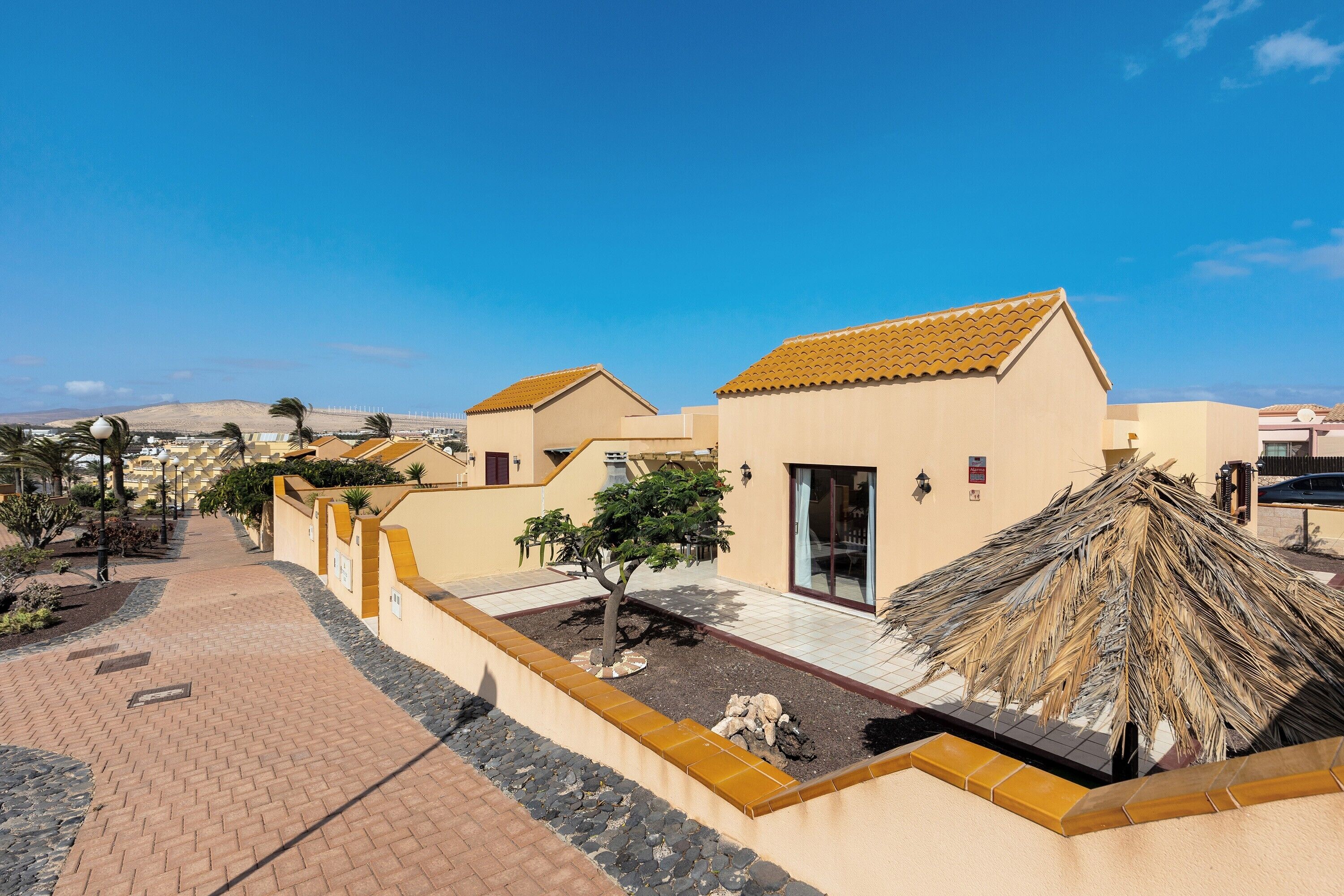 A courtyard with buildings, a pathway, and a thatched structure.
