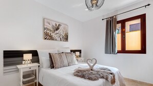 Une chambre à coucher comprenant un lit, des tables de chevet, une lampe fixée au mur, un élément décoratif mural et une fenêtre avec des rideaux.