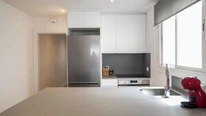 A modern kitchen with white cabinetry, a stainless steel refrigerator, a built-in oven, and a red appliance on the counter. - Spectacular Penthouse with Sagrada Familia Views (Barcelona)