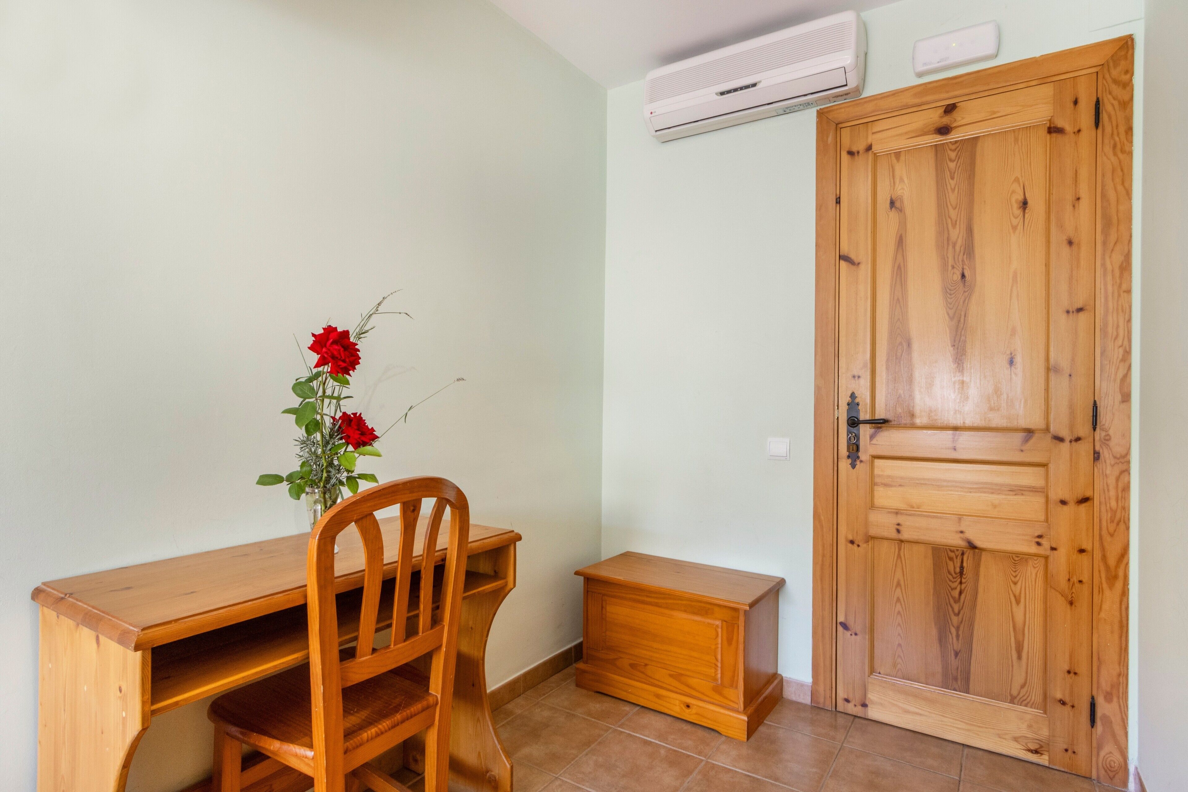 Una scrivania di legno con una sedia, un piccolo armadietto in legno e una porta di legno con maniglia.