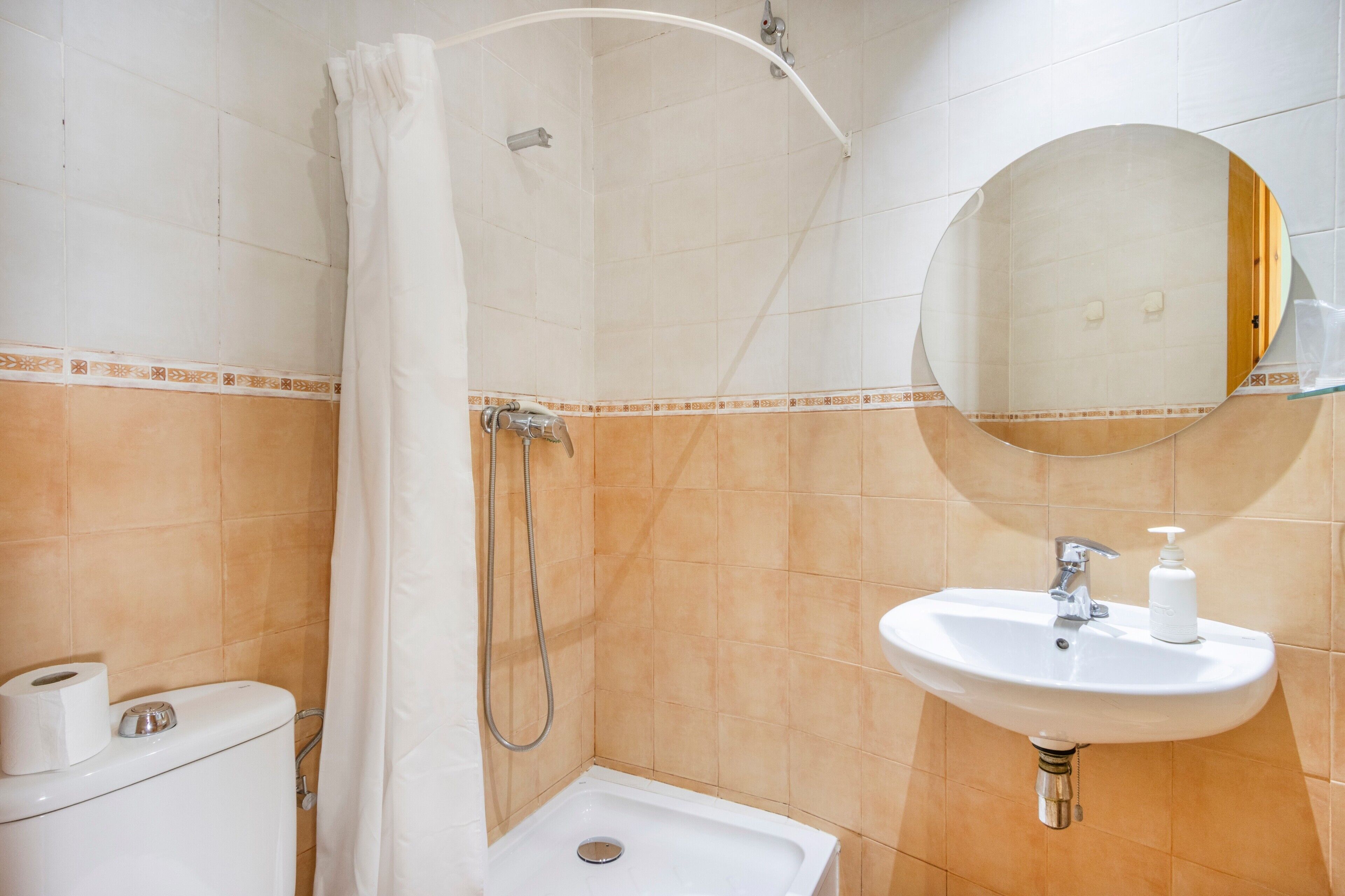 Une salle de bain équipée d’une douche, de toilettes, d’un lavabo et d’un miroir.