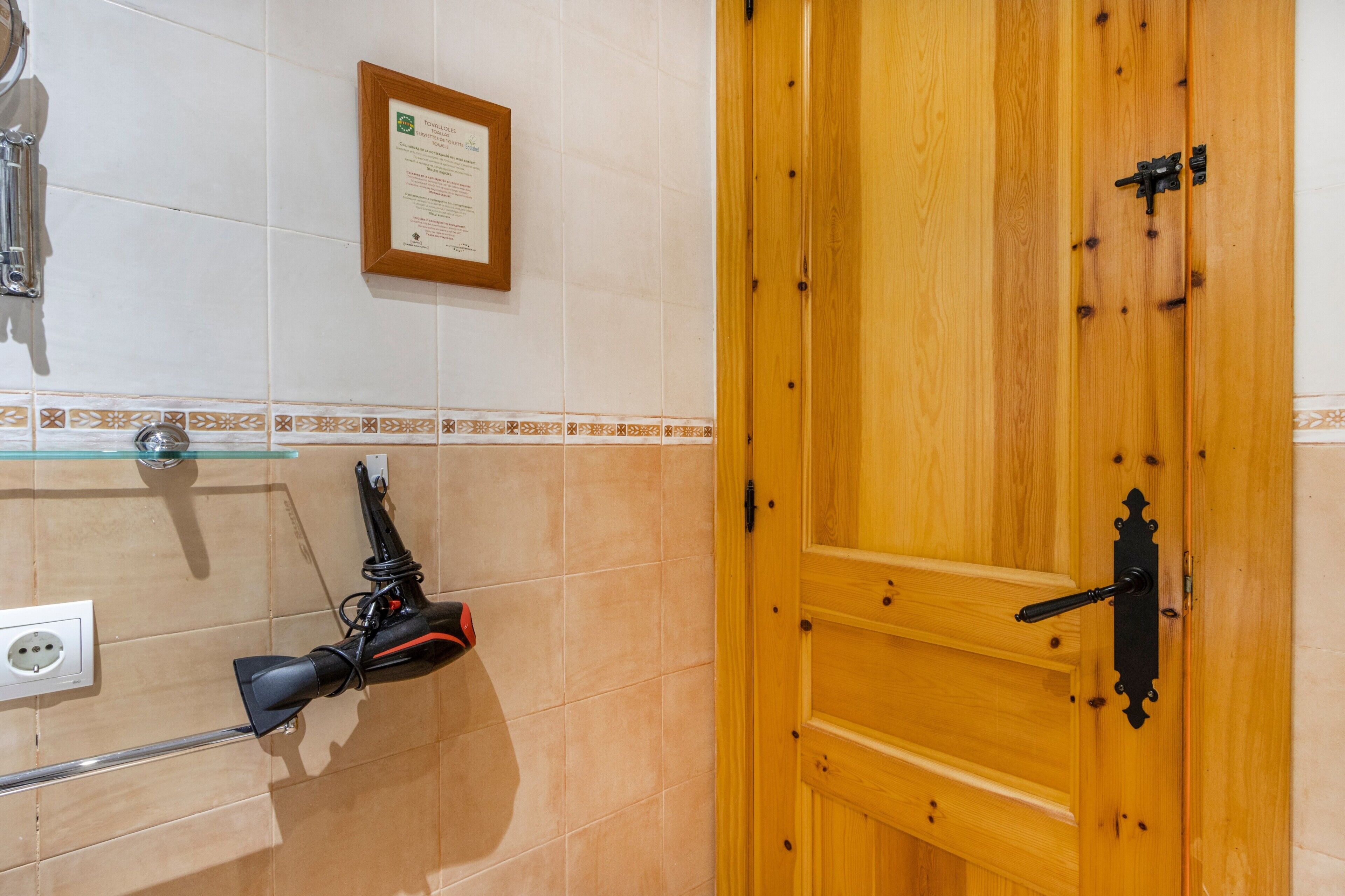 Un bagno con una porta in legno, un certificato incorniciato al muro e un porta asciugamani con un asciugamano.
