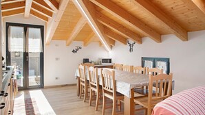 A dining area with a long table, wooden chairs, and a ceiling with exposed beams. - Holiday Home 'Sam Fiamet' with Mountain View, Shared Garden and Wi-Fi (GROSIO)